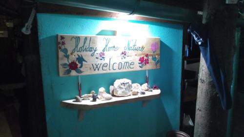 a blue wall with a shelf with rocks and a welcome sign at Holiday Home Nature Neno in Visoko