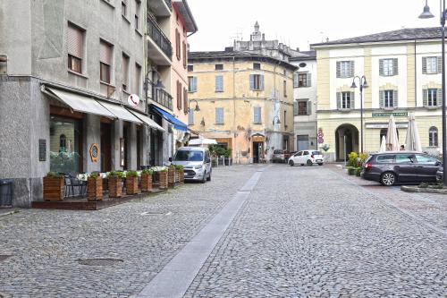 a cobblestone street in a city with cars parked at Albergo Gusmeroli in Tirano