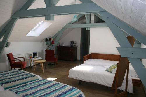 a attic room with two beds and a table at Au Relais de Chaussy in Chaussy