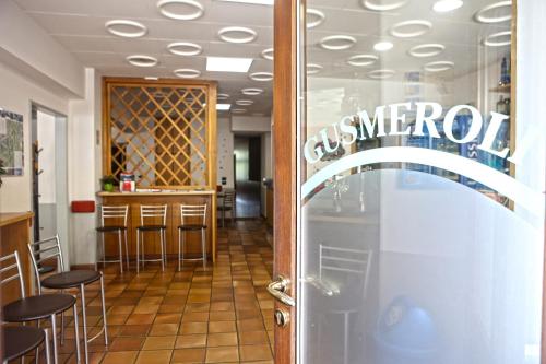 a restaurant with a bar with stools and a glass door at Albergo Gusmeroli in Tirano