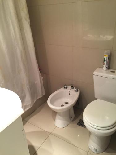 a white bathroom with a toilet and a sink at Apart de la Bahía con cochera in Bahía Blanca