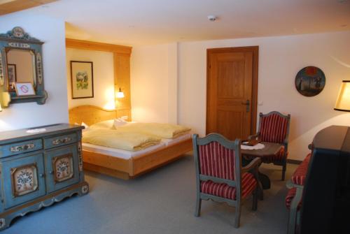 a bedroom with a bed and a table and chairs at Der Erlhof Restaurant & Landhotel in Zell am See