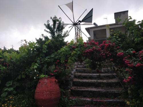 a windmill and stairs in a garden with flowers at Dionysus House Lasithi Plateau in Magoulás