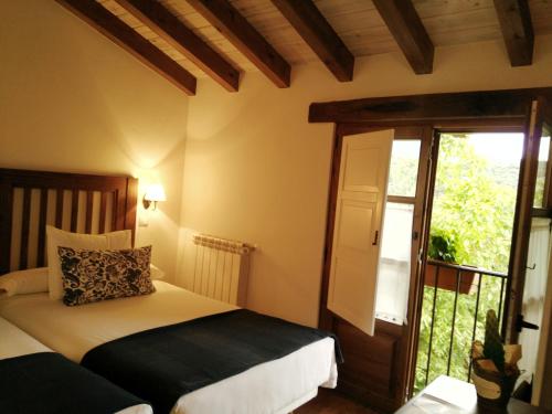 1 dormitorio con 2 camas y puerta corredera de cristal en Casa Fidela, en Lomeña