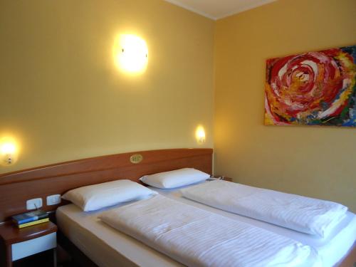 Hotel Ristorante Daino في بياتراموراتا: غرفة نوم بسريرين ولوحة على الحائط