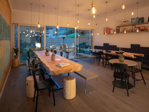 un restaurant avec une grande table et des chaises en bois dans l'établissement Glocal Torbole, à Nago-Torbole