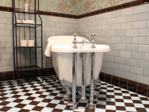 a bath tub in a bathroom with a checkered floor at Titchwell Manor Hotel in Titchwell