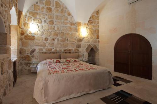 a bedroom with a bed and a stone wall at Kasr-i Nehroz Hotel in Midyat
