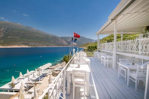a deck with white tables and chairs next to the water at Club Çapa Hotel in Kas