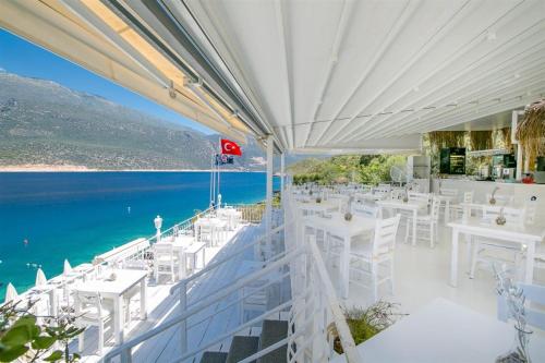 a restaurant with white tables and chairs and the water at Club Çapa Hotel in Kas