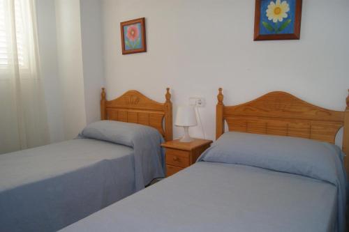 1 dormitorio con 2 camas y mesa con lámpara en Apartamentos San Miguel, en Alcossebre