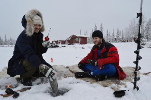 two men are sitting in the snow at Camp Alta Kiruna in Kiruna
