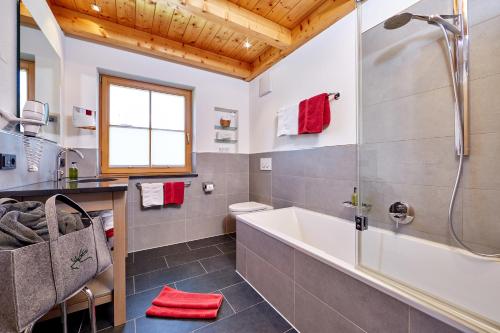 a bathroom with a tub and a shower and a sink at Ferienhaus Alpinissimo in Oberammergau