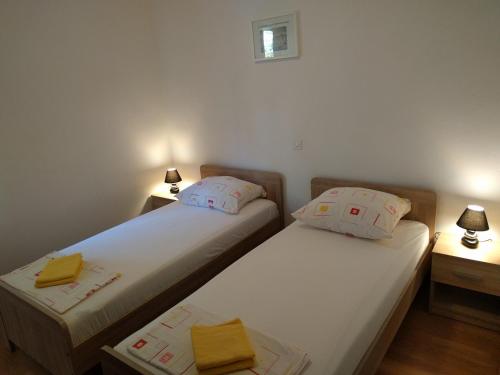 two beds in a small room with two lamps at Apartments Kuzman in Dubrovnik
