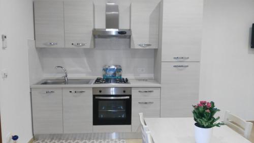 een keuken met witte kasten, een wastafel en een tafel bij Aria di Casa in Porto Cesareo