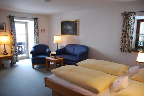 a hotel room with two beds and a chair at Der Erlhof Restaurant & Landhotel in Zell am See
