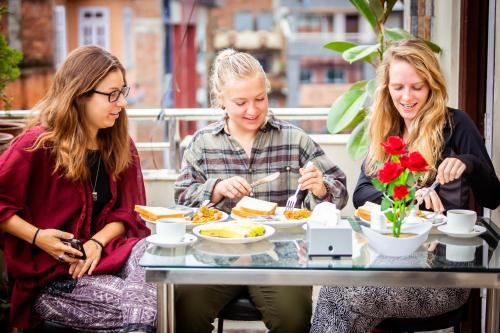 a group of three women sitting at a table eating food at 8848 Hostel in Kathmandu