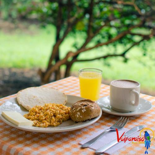 a plate of food with bread and a cup of orange juice at Finca Hotel Valparaíso in Armenia