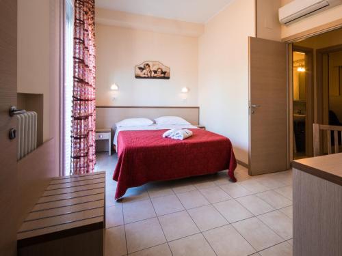 a hotel room with a bed with a red blanket at Appartamenti Lira in Cattolica