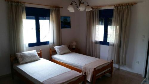 a bedroom with two beds and two windows at Vlachogiannis EL Estate in Skala Rachoniou