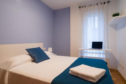 a bedroom with a white bed with a blue blanket at Alojamiento Santa Maria in Milladoiro