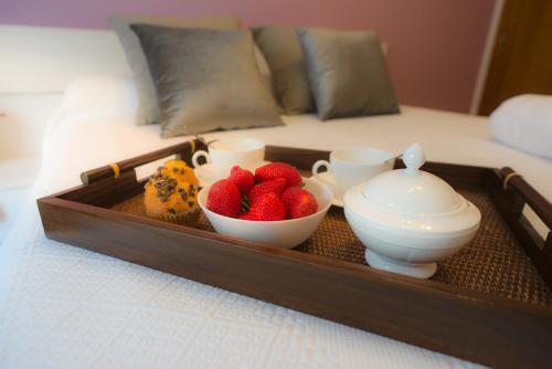 a tray with cups and strawberries and cookies on a bed at Alojamiento Santa Maria in Milladoiro
