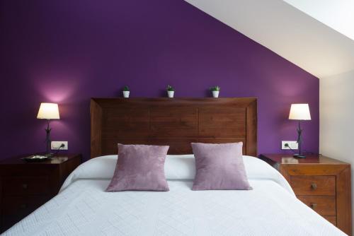 a purple bedroom with a white bed with two pillows at Alojamiento Santa Maria in Milladoiro