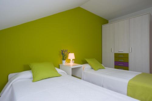two beds in a room with green walls at Alojamiento Santa Maria in Milladoiro
