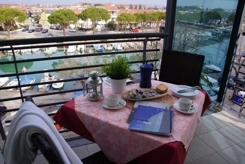 a table with a laptop and a plate of food on a balcony at Residence Aprilia in Grado