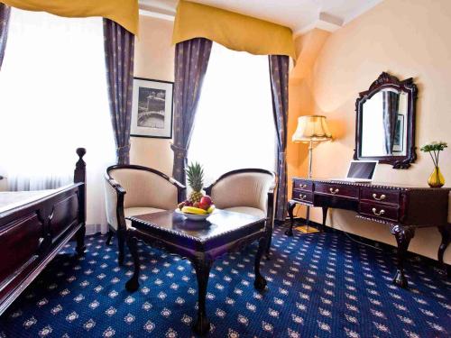 a room with a bed and a table and a mirror at Pytloun Old Armoury Hotel Prague, Stará Zbrojnice in Prague