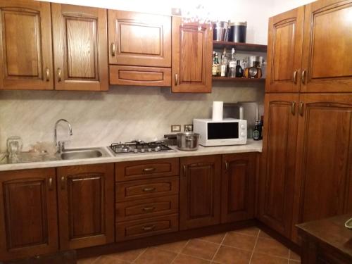 uma cozinha com armários de madeira, um lavatório e um micro-ondas em cimmo em Tavernole sul Mella