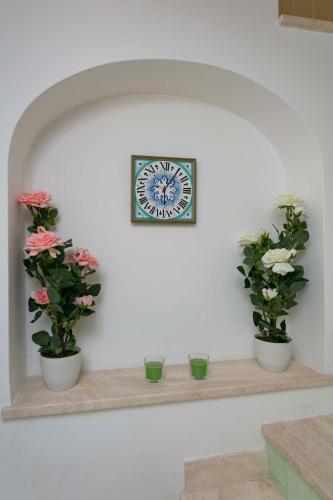 a clock on a wall with three potted plants on a shelf at Casa Pamela in Capri
