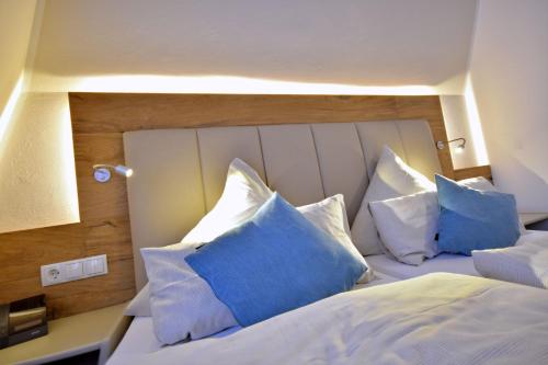 a bedroom with a white bed with blue pillows at Hotel & Restaurant Zum Deutschen Hause in Kirchhatten