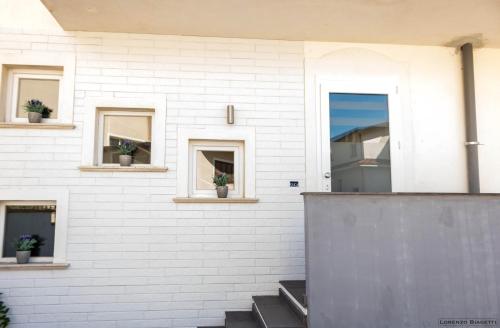 a white brick house with potted plants in windows at B&B Geolja in Gioia Tauro