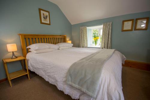 a bedroom with a white bed with a window at Rye Hill Farm in Hexham