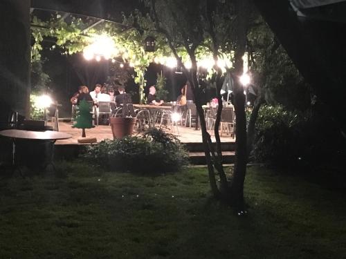 a group of people sitting at tables in a garden at night at Hotel Elisabeth in La Vancelle