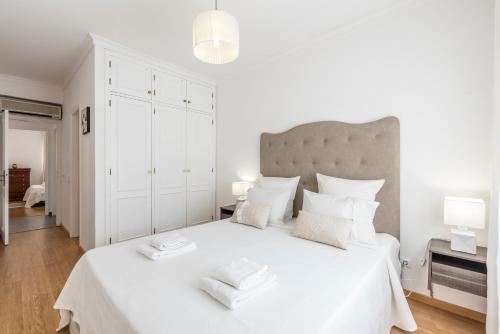 1 dormitorio blanco con 1 cama blanca grande y 2 toallas en Albufeira Oldtown 330ft Beach Parking AC Wifi, en Albufeira