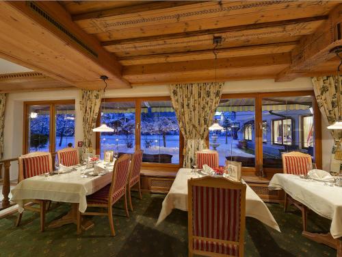 a dining room with tables and chairs and windows at Alpenhotel Tirolerhof in Neustift im Stubaital