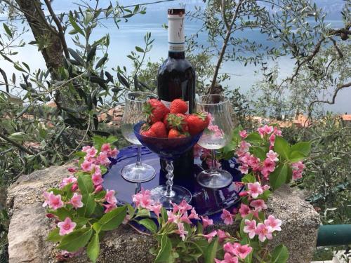 una botella de vino y dos copas de vino y fresas en Appartamento Soldo, en Castelletto di Brenzone