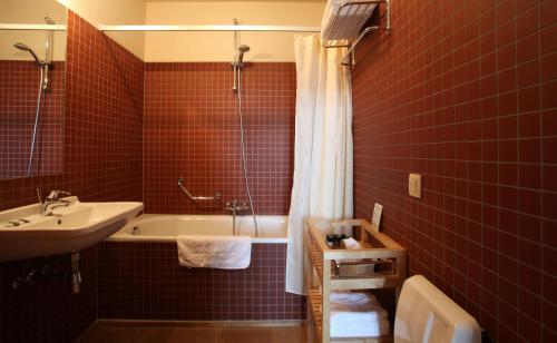 La salle de bains est pourvue de carrelage rouge, d'une baignoire et d'un lavabo. dans l'établissement 'S Hertogenmolens Hotel, à Aarschot