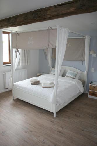 una camera con un letto bianco a baldacchino di La Ferme Remue a Rixensart