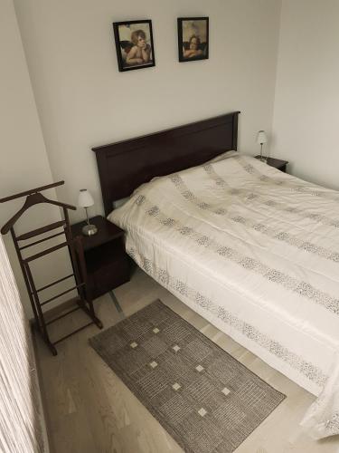 a bedroom with a bed and a night stand with a table at Miško apartamentai 50m2 in Juodkrantė