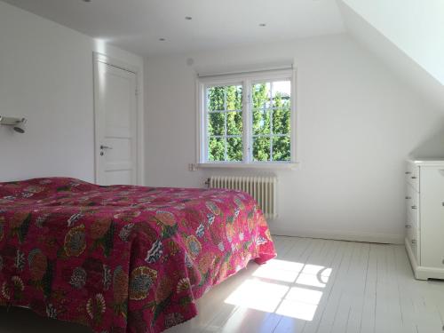 a white bedroom with a bed and a window at Family villa near sea and Stockholm city in Stockholm