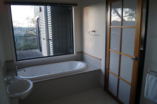 baño con bañera, lavabo y ventana en River Vineyard Retreat, en Grindelwald