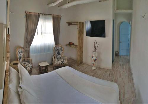 a bedroom with a bed and two chairs and a window at Casa Hotel Santa Helena Boutique in Villa de Leyva