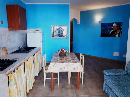 a kitchen with a table and a sink and blue walls at Gli Ulivi in Valledoria