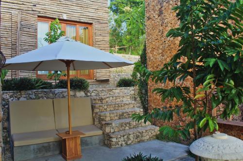 a bench with an umbrella next to a building at Kabeh Jati Garden Villa & Restaurant in Nusa Penida