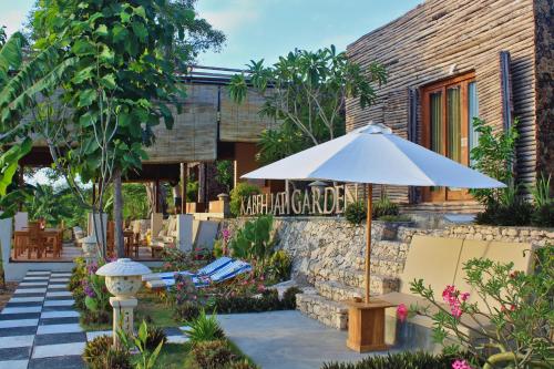 an umbrella and chairs in front of a building at Kabeh Jati Garden Villa & Restaurant in Nusa Penida