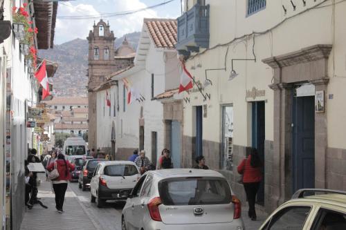 a street with cars and people walking down the street at Hostal Alfredo's Palace in Cusco