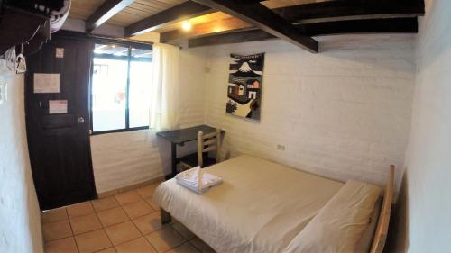 a small room with a bed and a window at Hostal L'Auberge Inn in Quito